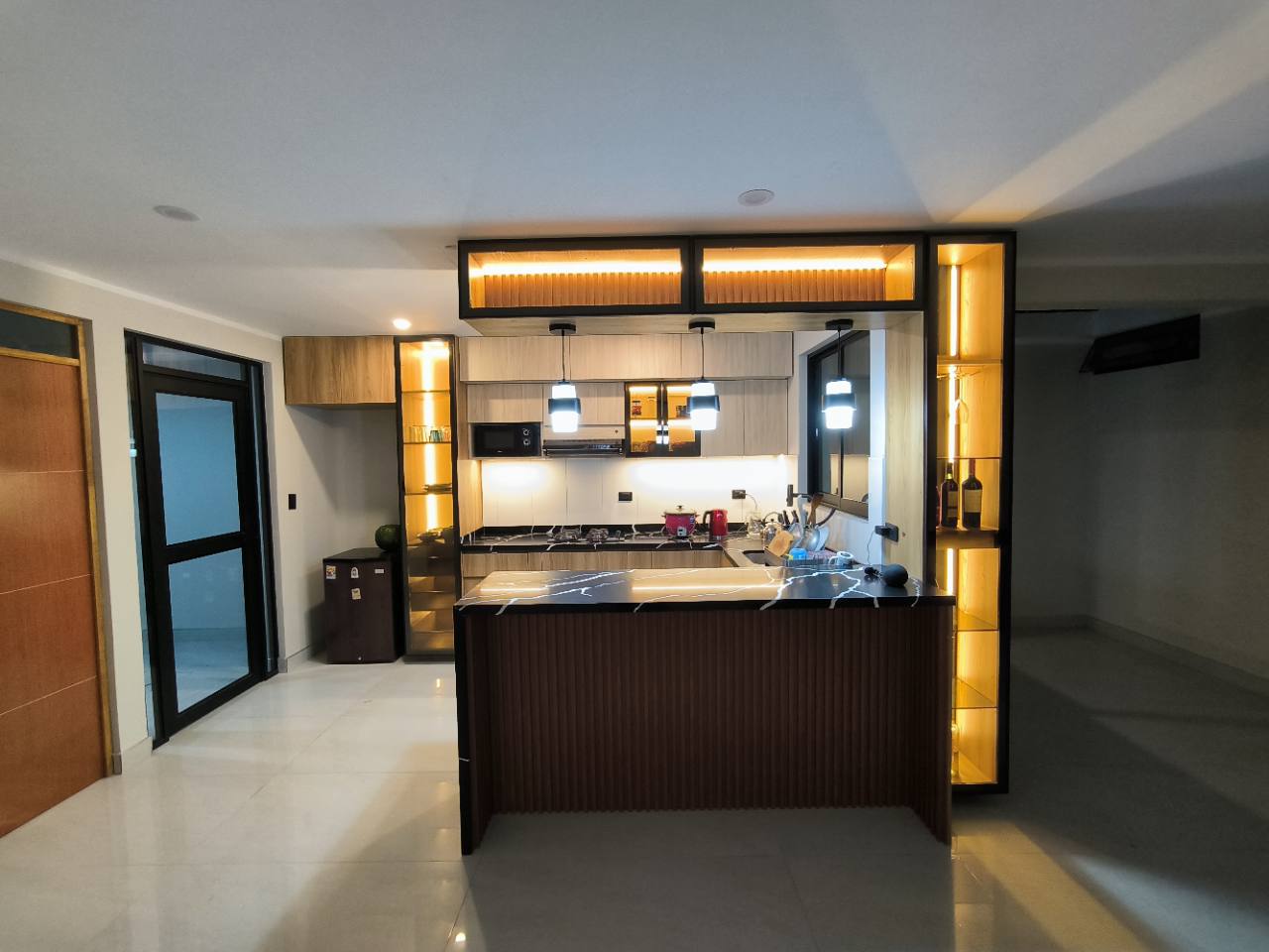 Cocina integral a medida con isla, vitrinas iluminadas y acabados en madera